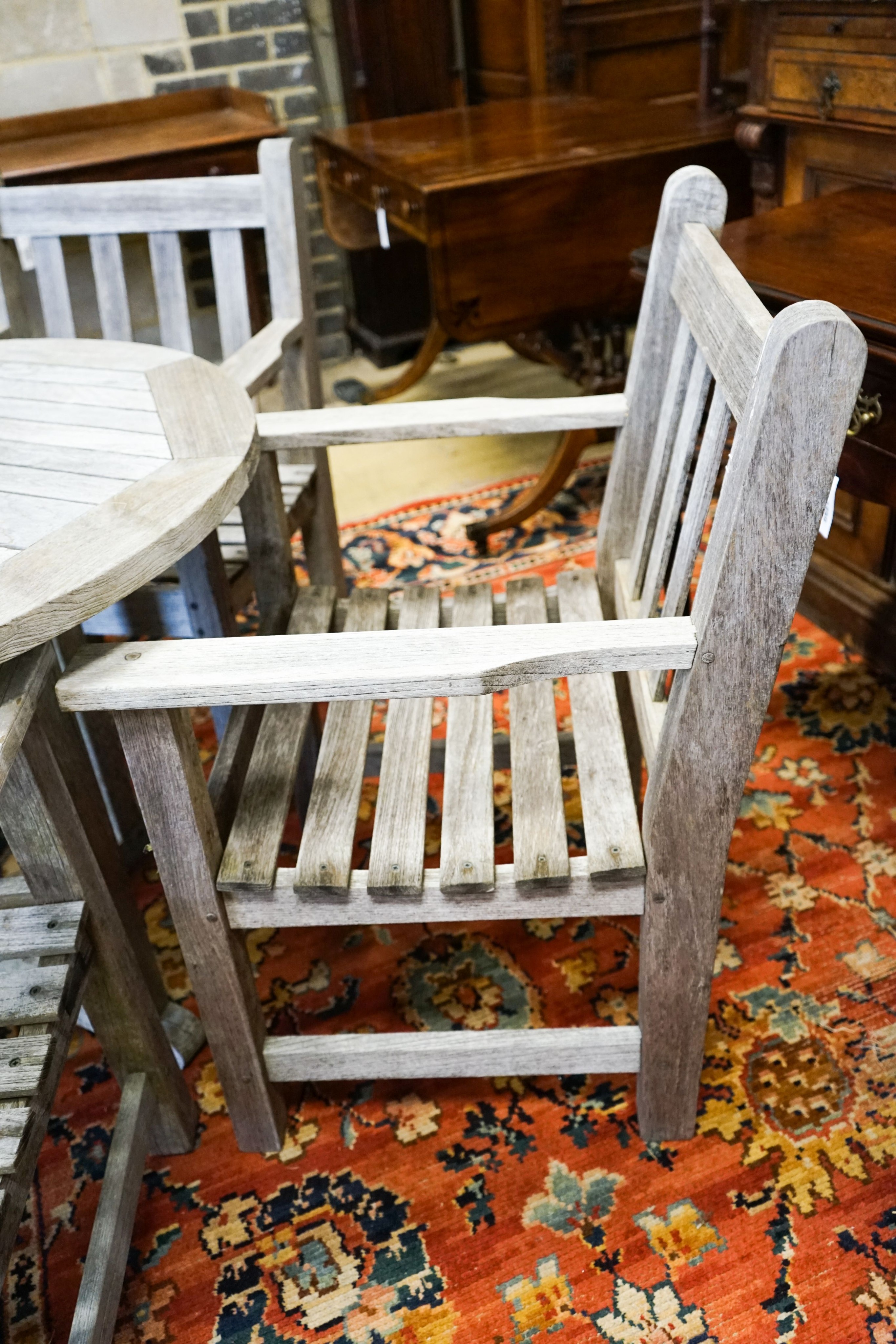 A set of four teak garden chairs and a circular parasol table, diameter 91cm chairs width 60cm